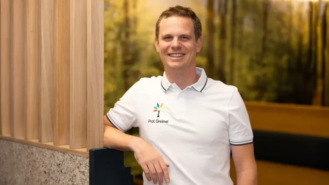 Prof. Dr. Felix Greimel – Facharzt für Orthopädie lehnt an einer Wand im Wartebereich