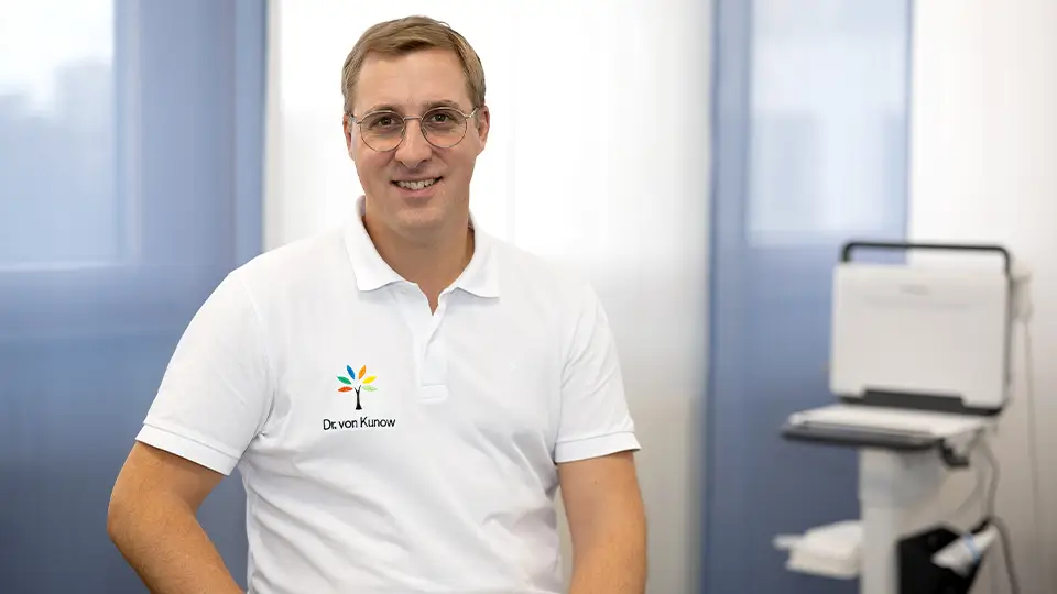 Porträt von Dr. Frederik von Kunow – Facharzt für Orthopädie sitzend in einem Behandlungsraum